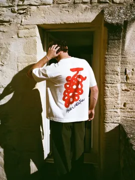 A designer tee with a red back print, worn in a stone doorway