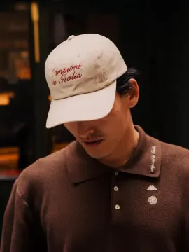 An embroidered cream cap with a brown knit polo