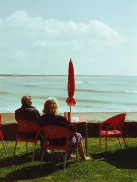 A red umbrella and chairs on a seaside terrace